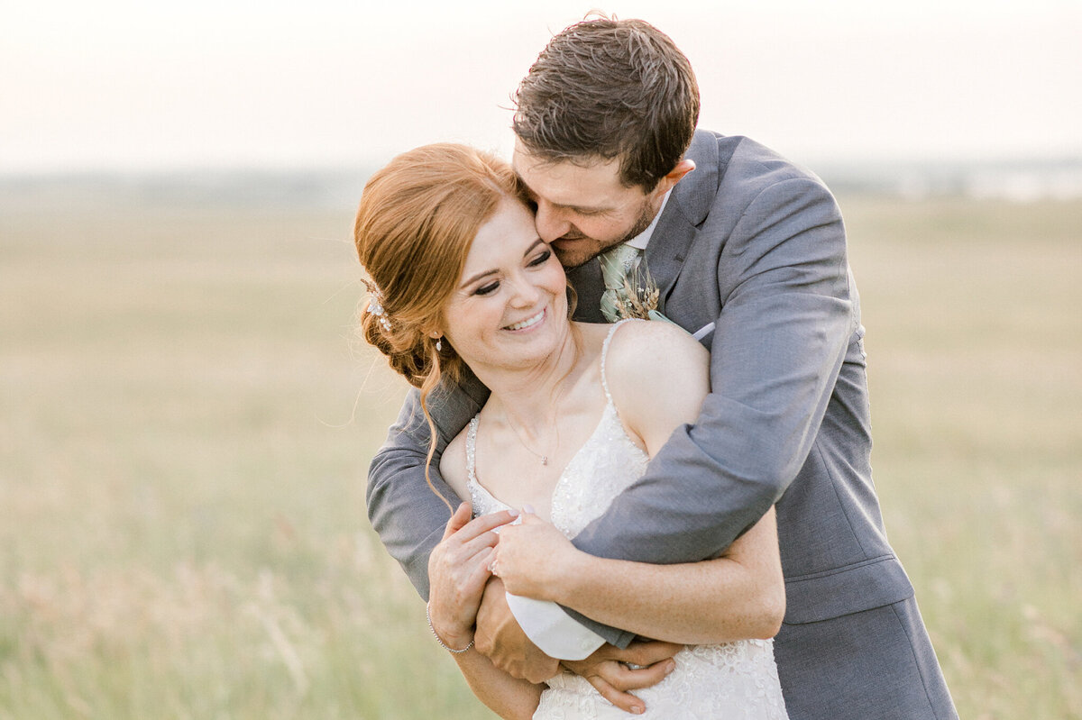 Groom hugging bride captured by Sweetlight Photography, fine art and romantic wedding photographer in Central Alberta. Featured on the Bronte Bride Vendor Guide.