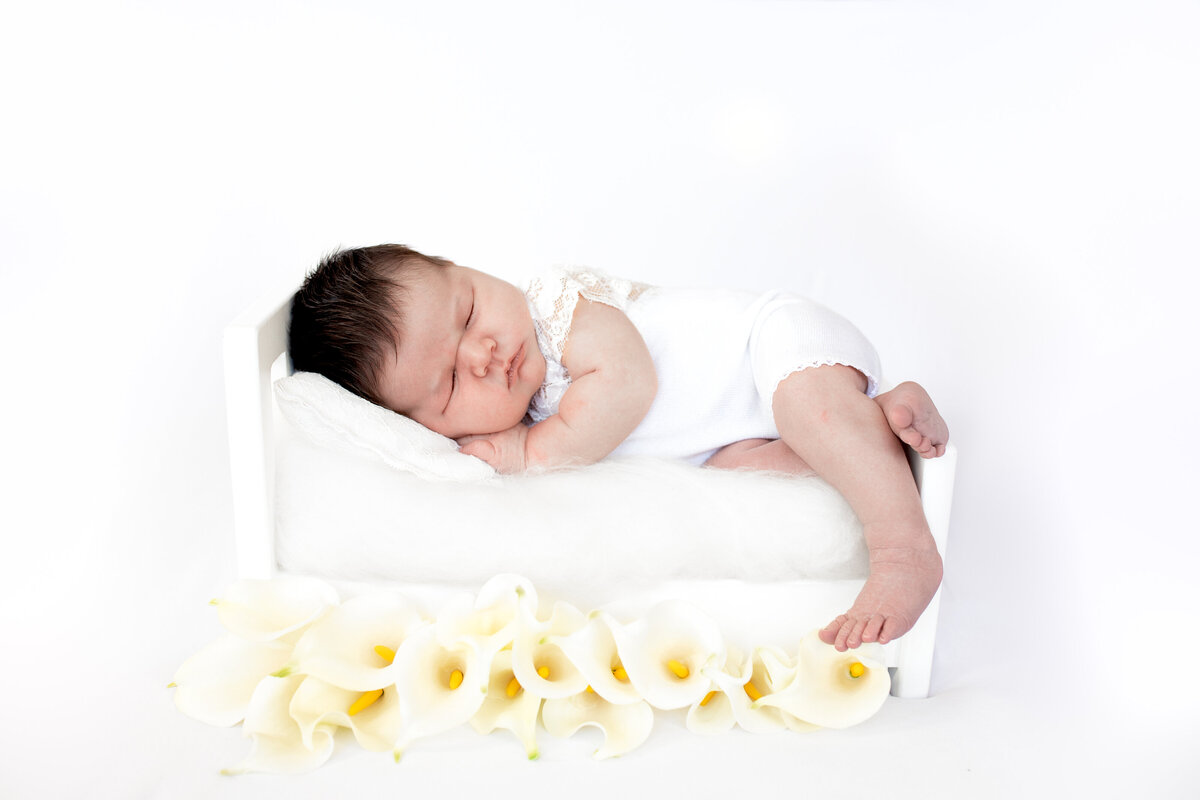 Newborn baby girl sleeping posed on a prop bed with flowers by Hobart Newborn Photographer Lauren Vanier