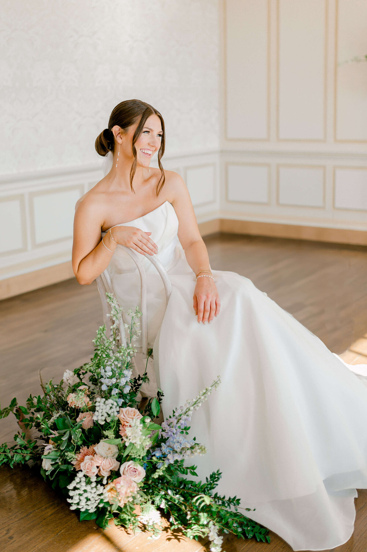 A bride sits on a chair in a room with a bouquet of flowers at DAR.