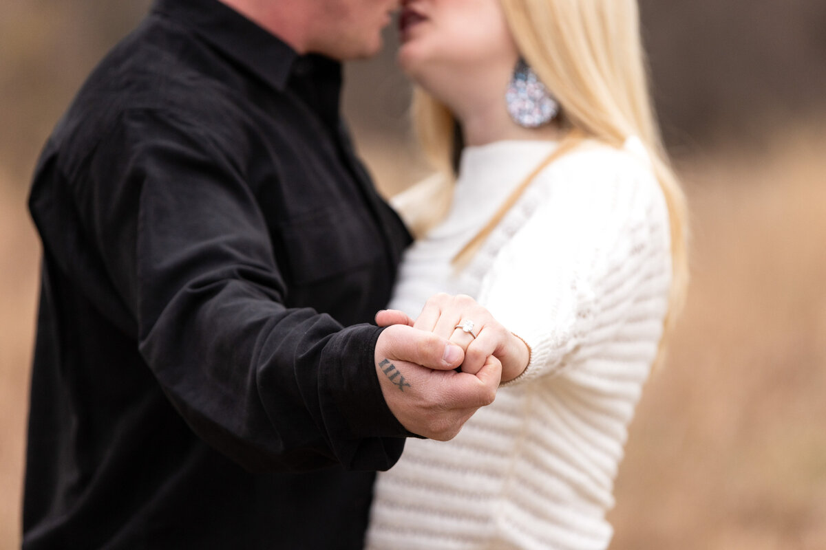 couple about to kiss showing engagement ring