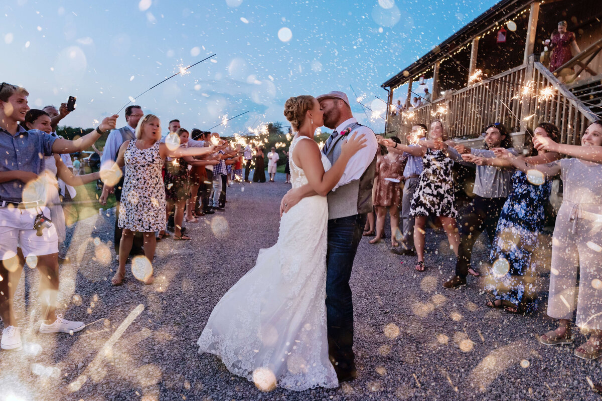 Bride and groom kissing with guests holding sparklers