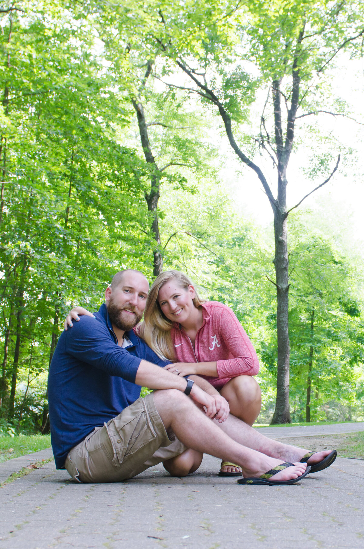 Engaged couple seated on brick walkway at Twin Lakes Park in Greensburg, PA