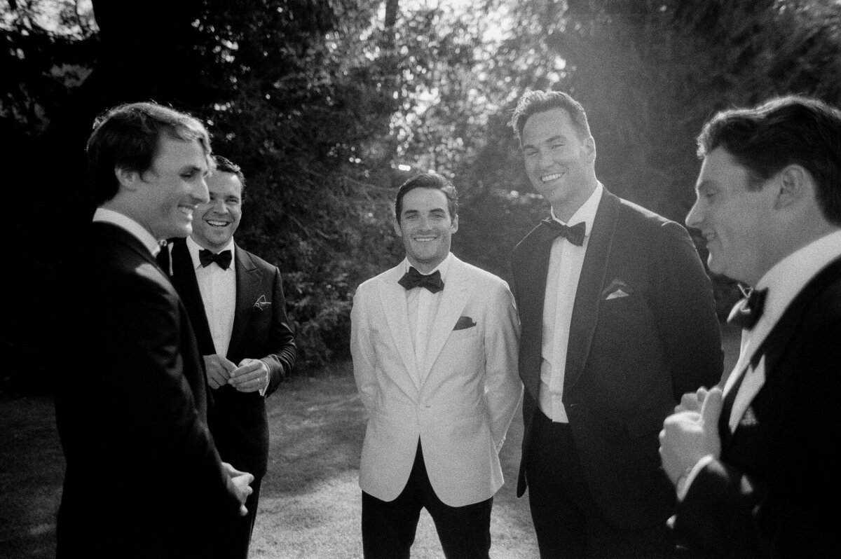 Black and white photo of the groom standing amongst the groomsmen.  