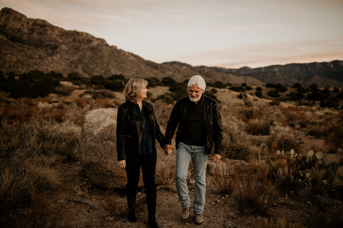 couple holding hands and walking in the desert