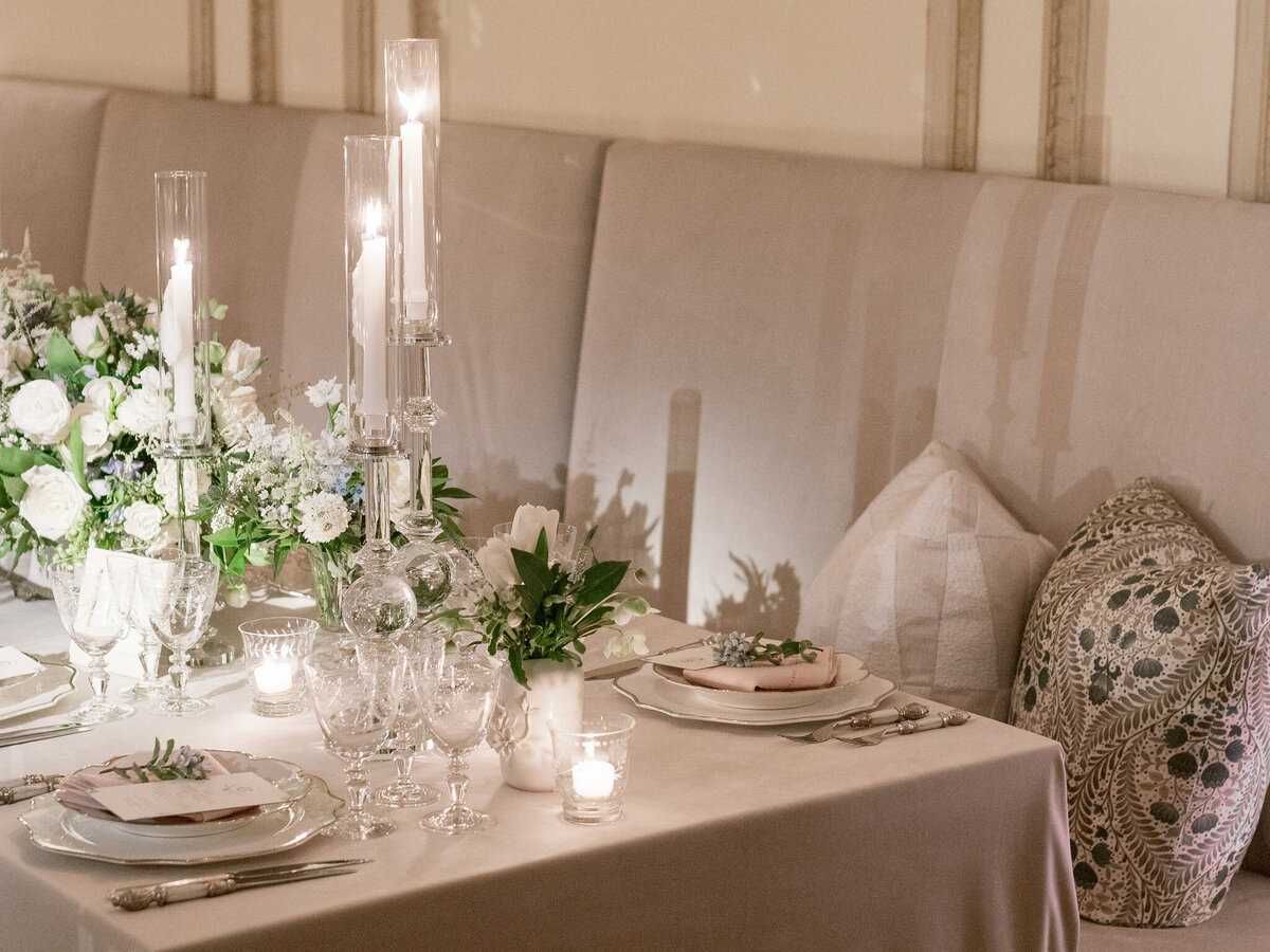Luxuriously decorated wedding dinner table with tall candlesticks, white flowers, and crystal glassware.