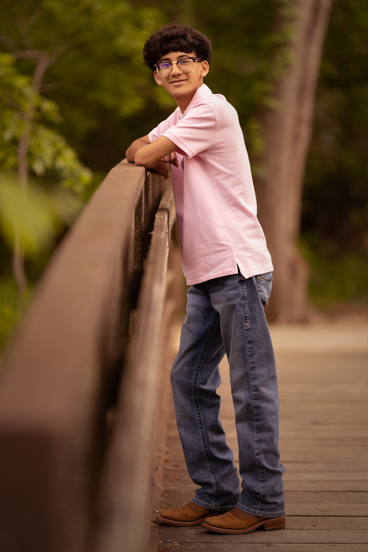 A young man enjoys a moment on a bridge during a family portrait session with a Dallas family photographer, showcasing casual elegance.
