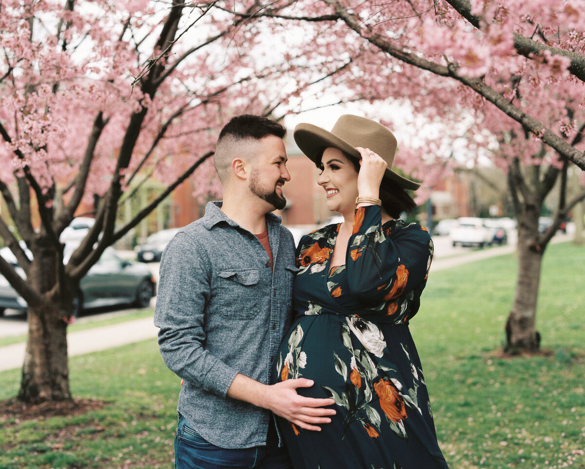 Expecting parents pose under cherry blossom trees