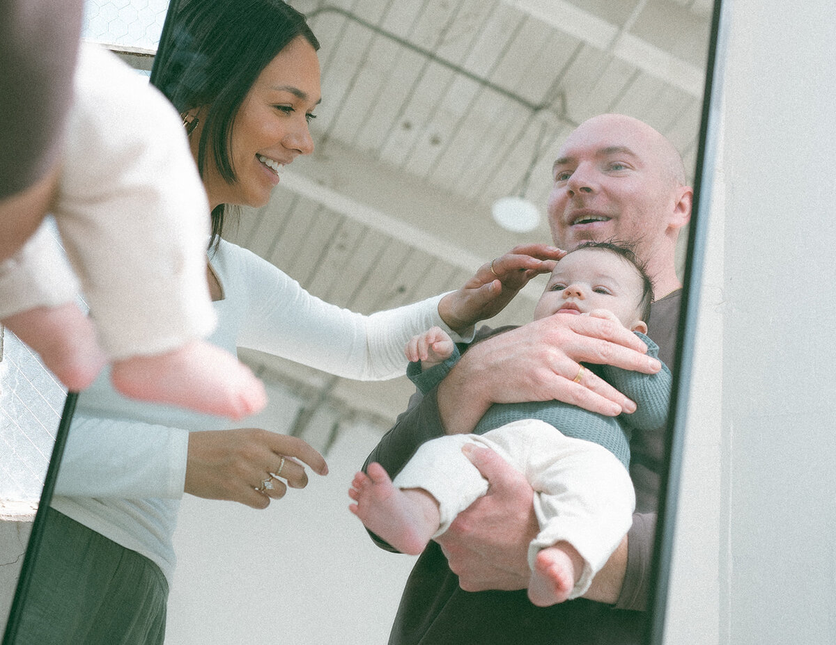 Parents smiling with newborn during candid Orange County family photography session.