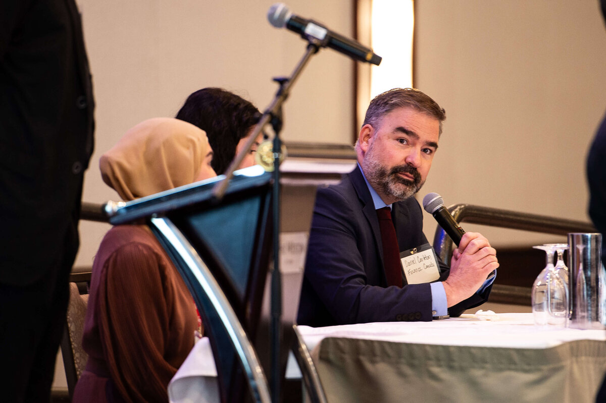 Ottawa event photos showing a man in a blue suit speaking into microphone during question period at a corporate conference. Captured by JEMMAN Photography COMMERCIAL