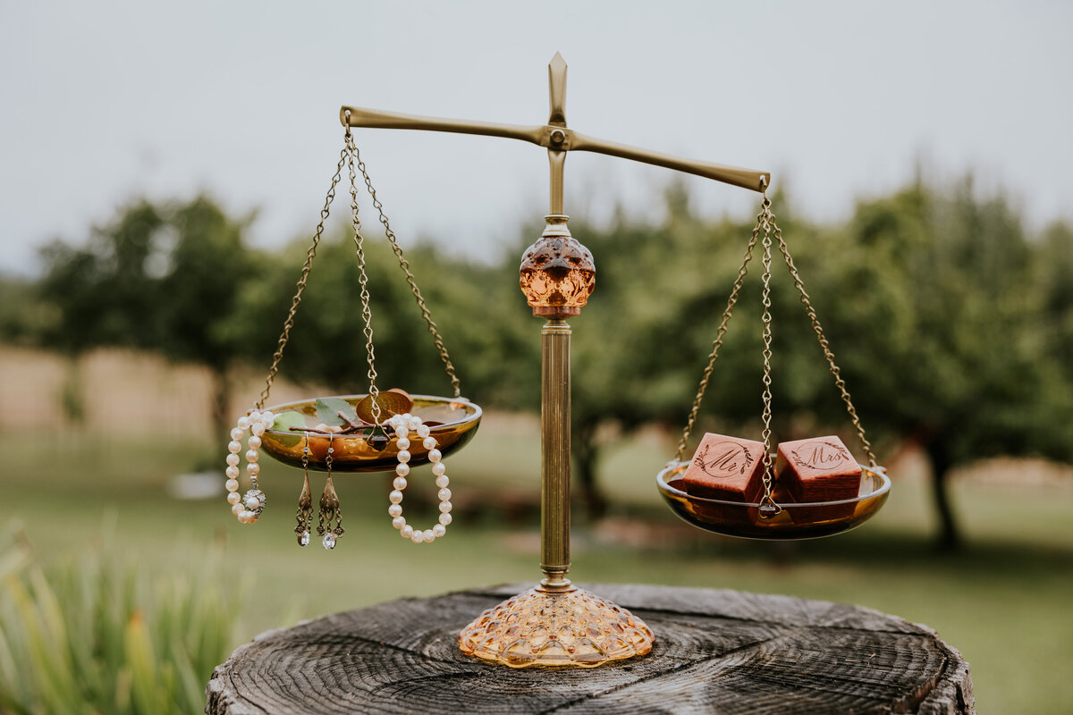 Bridal jewelry and wedding ring boxes sit in a old fashioned weight balancer.