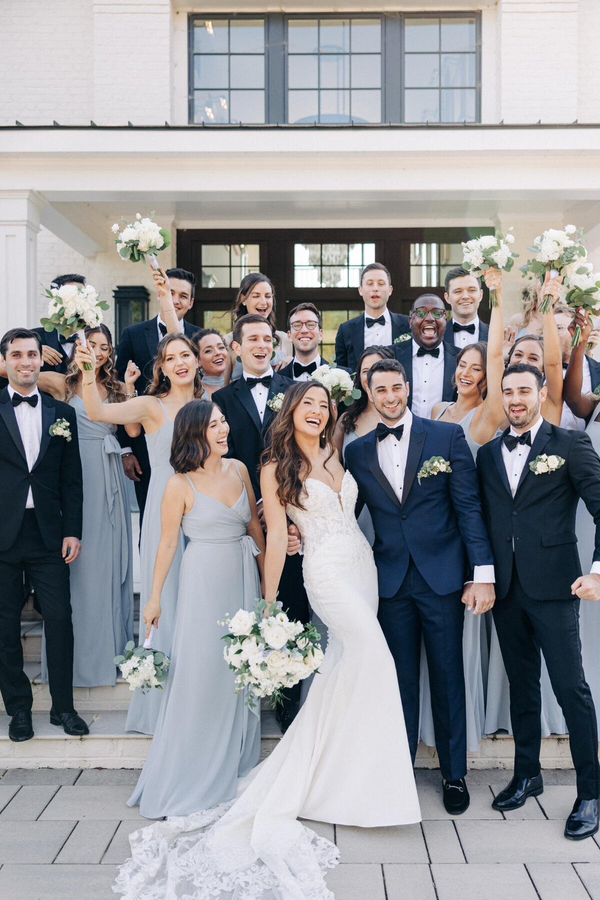 A joyful wedding party posing for a photo, featuring a bride and groom with their bridesmaids and groomsmen in coordinated attire.