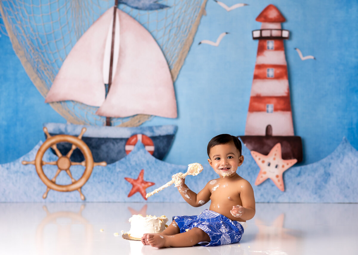 One year old Tampa baby enjoying a personalized luxury cake smash session with sail boat decorations