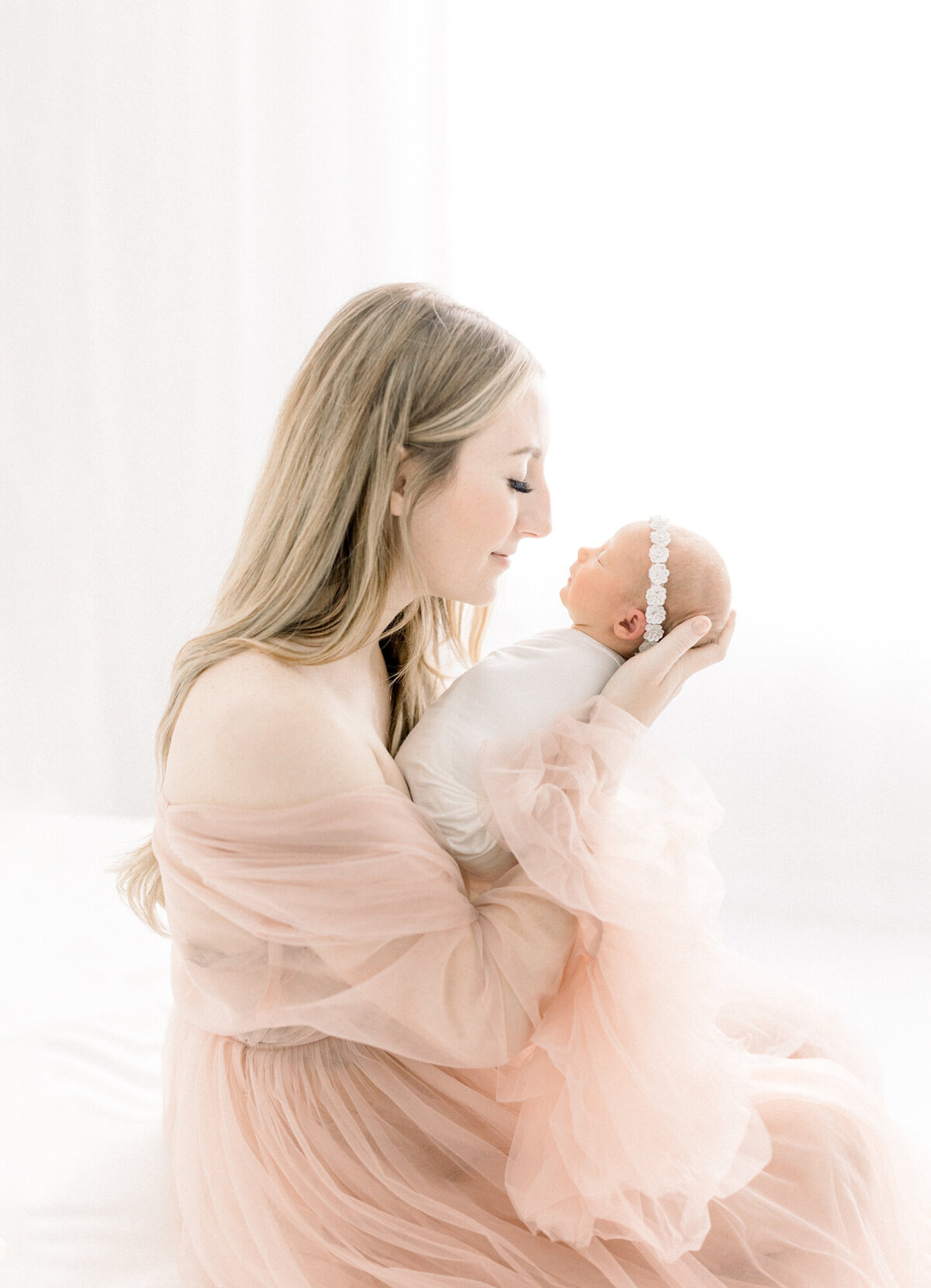 Portrait of a newborn baby wrapped and being held by her mother.