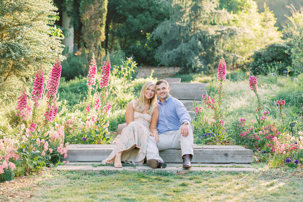 couple smiles sitting on steps at their engagement session at the georgia state bontanical gardens 