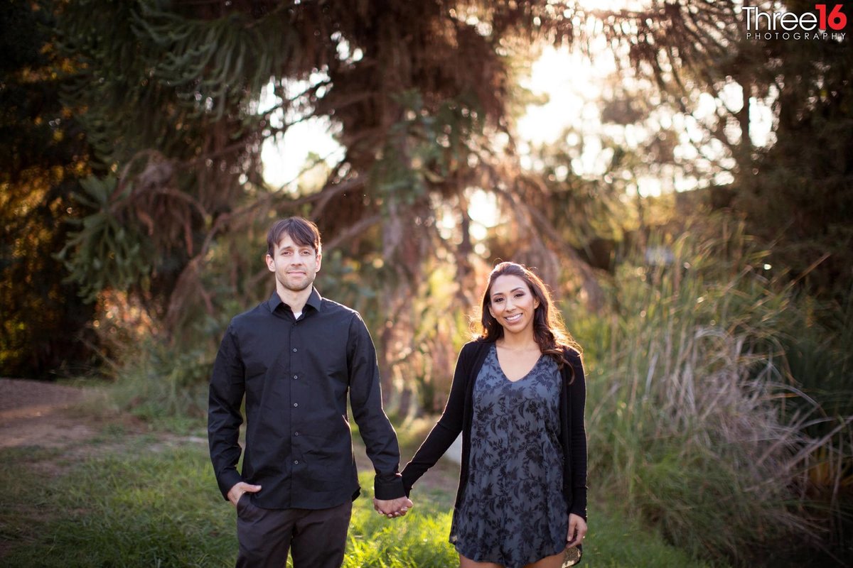 Bride and Groom to be hold hands at the Fullerton Arboretum during a photo session
