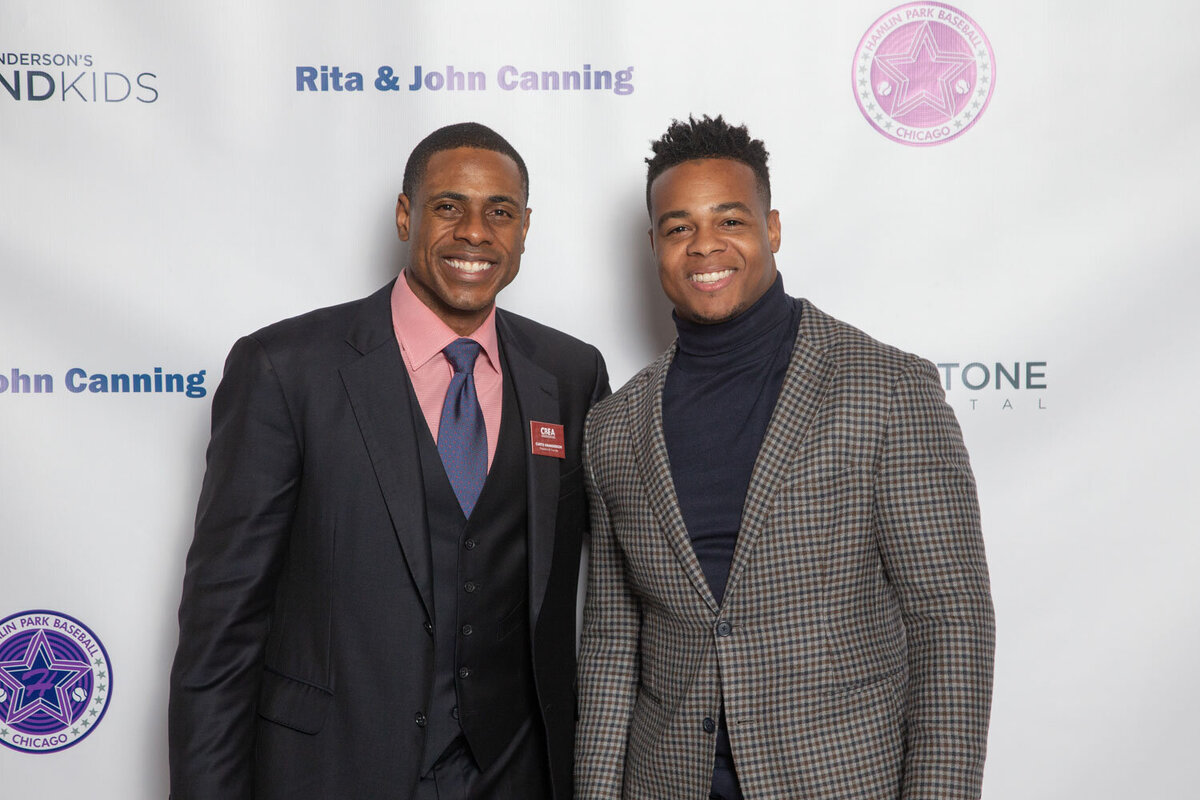 Two men smiling at a step-and-repeat photo backdrop