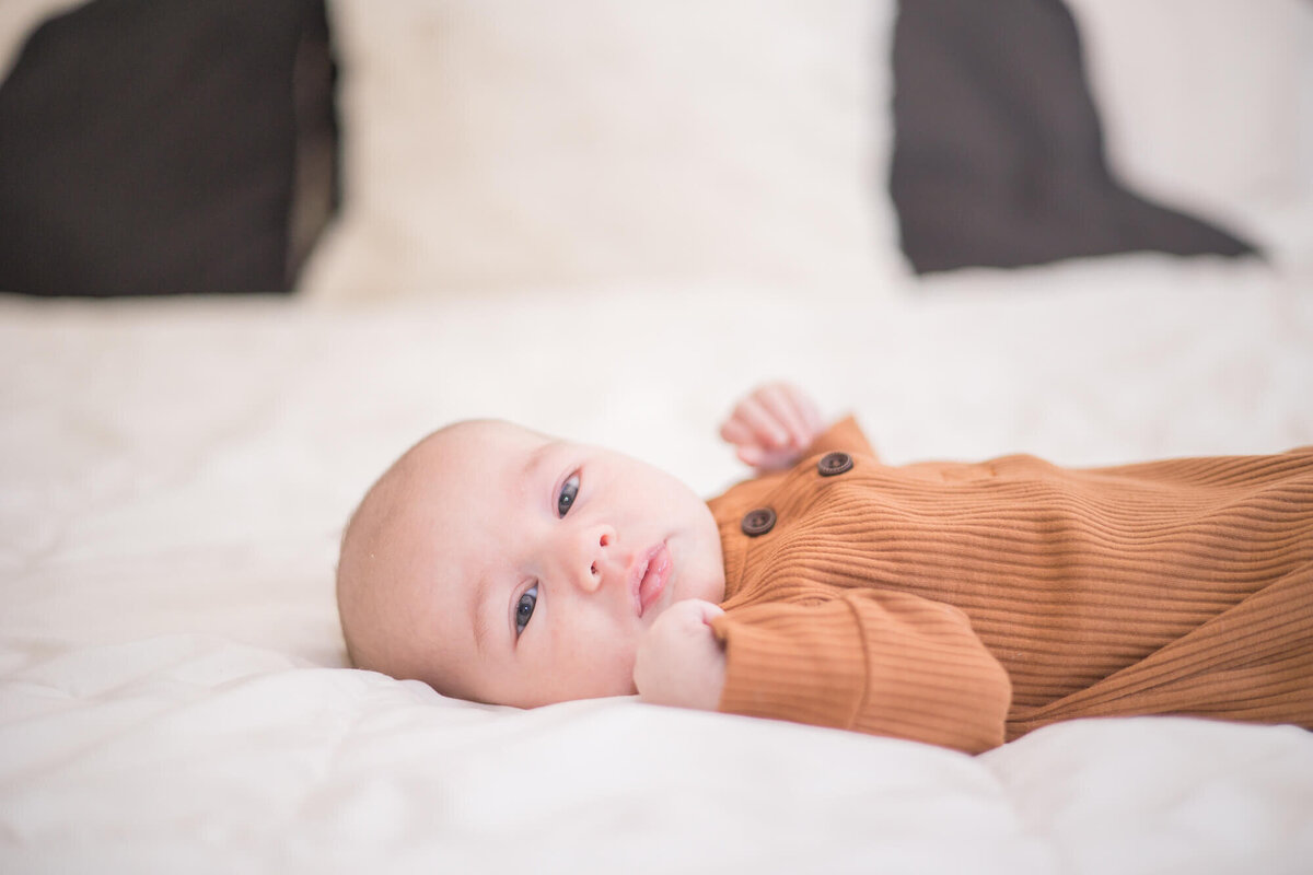 newborn baby boy in an orange-brown outfit on a bed