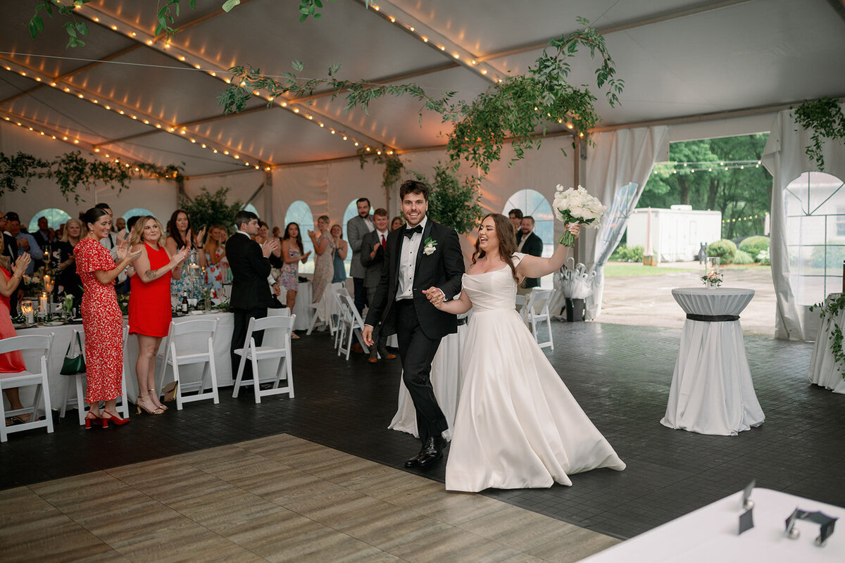 Bride and groom dancing at The Morris Estate reception tent with greenery décor and excited guests.