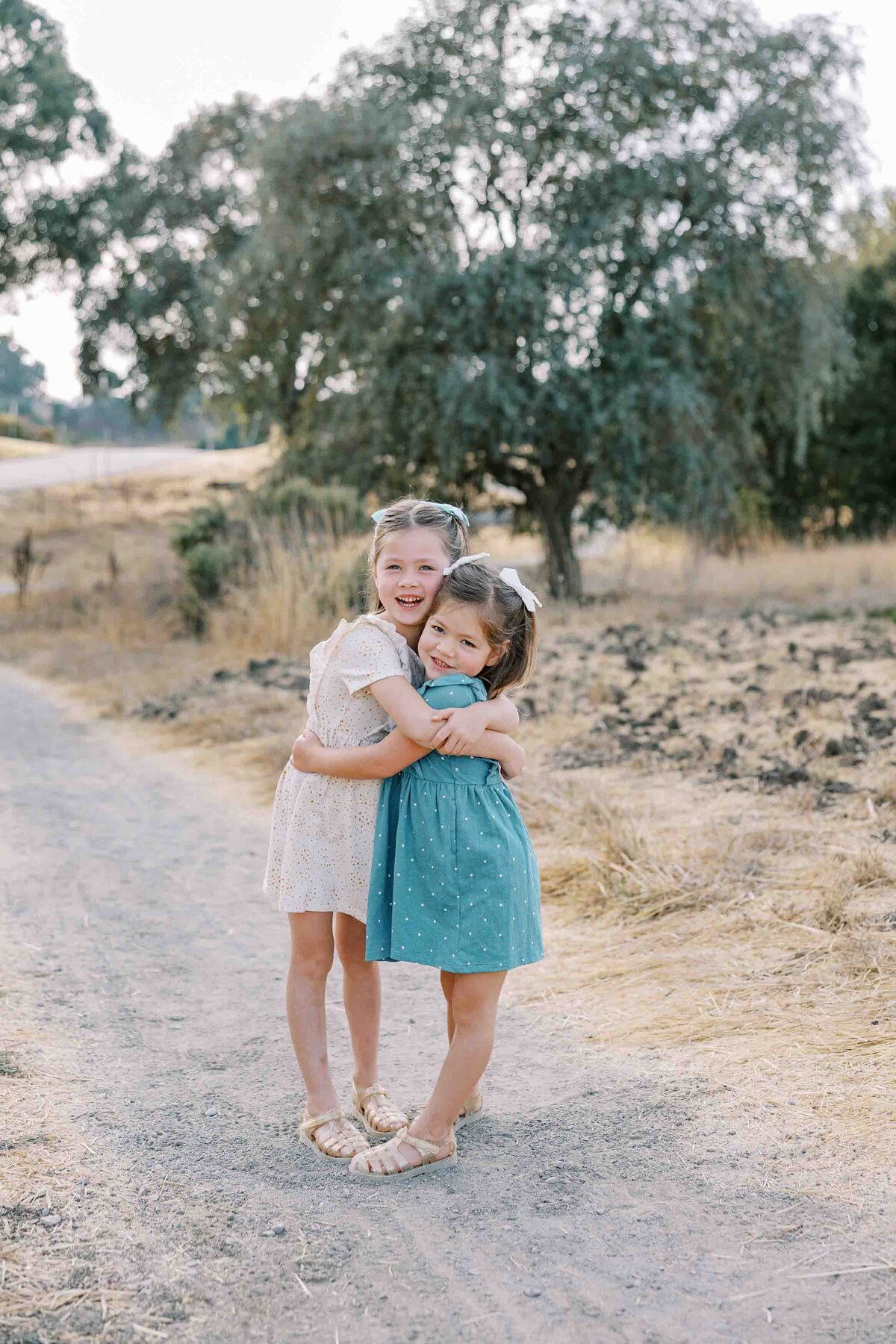 sisters wearing dresses and bows in their hair and hugging