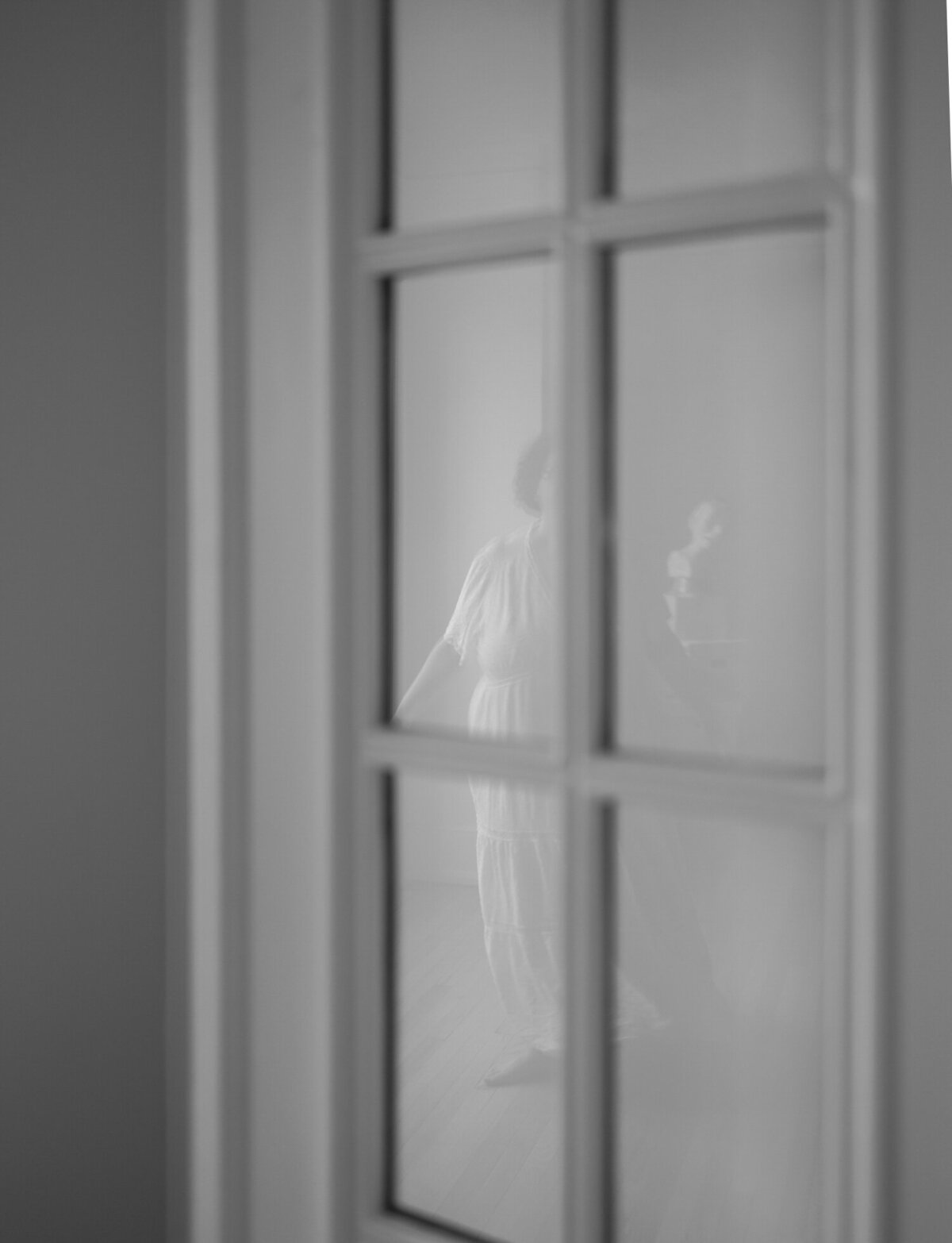 creative film branding photography, reflection of woman in white dress through glass door