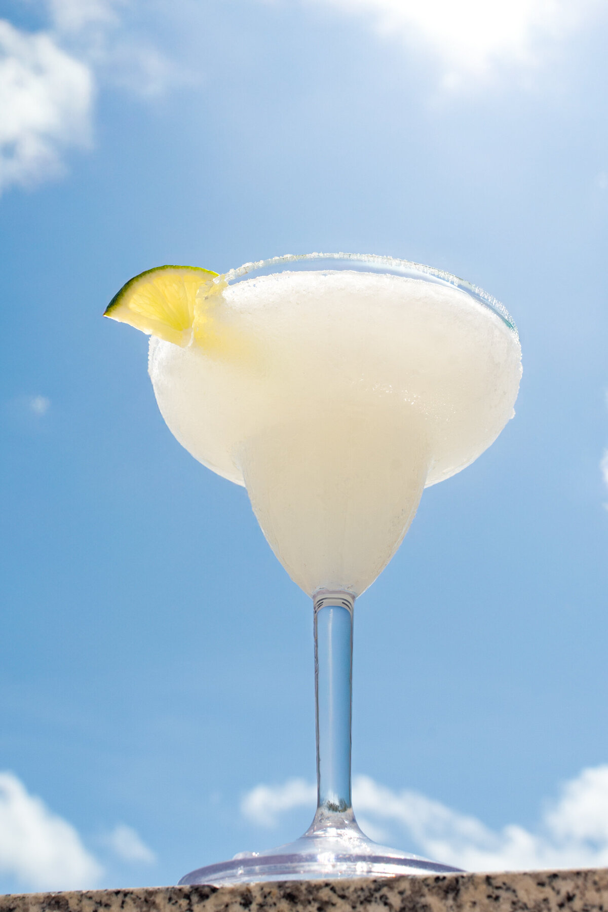 A frozen margarita with a lime wedge and a salt rim is photographed against a full sun day in Cancun, Mexico for the Riu Latino Hotel.