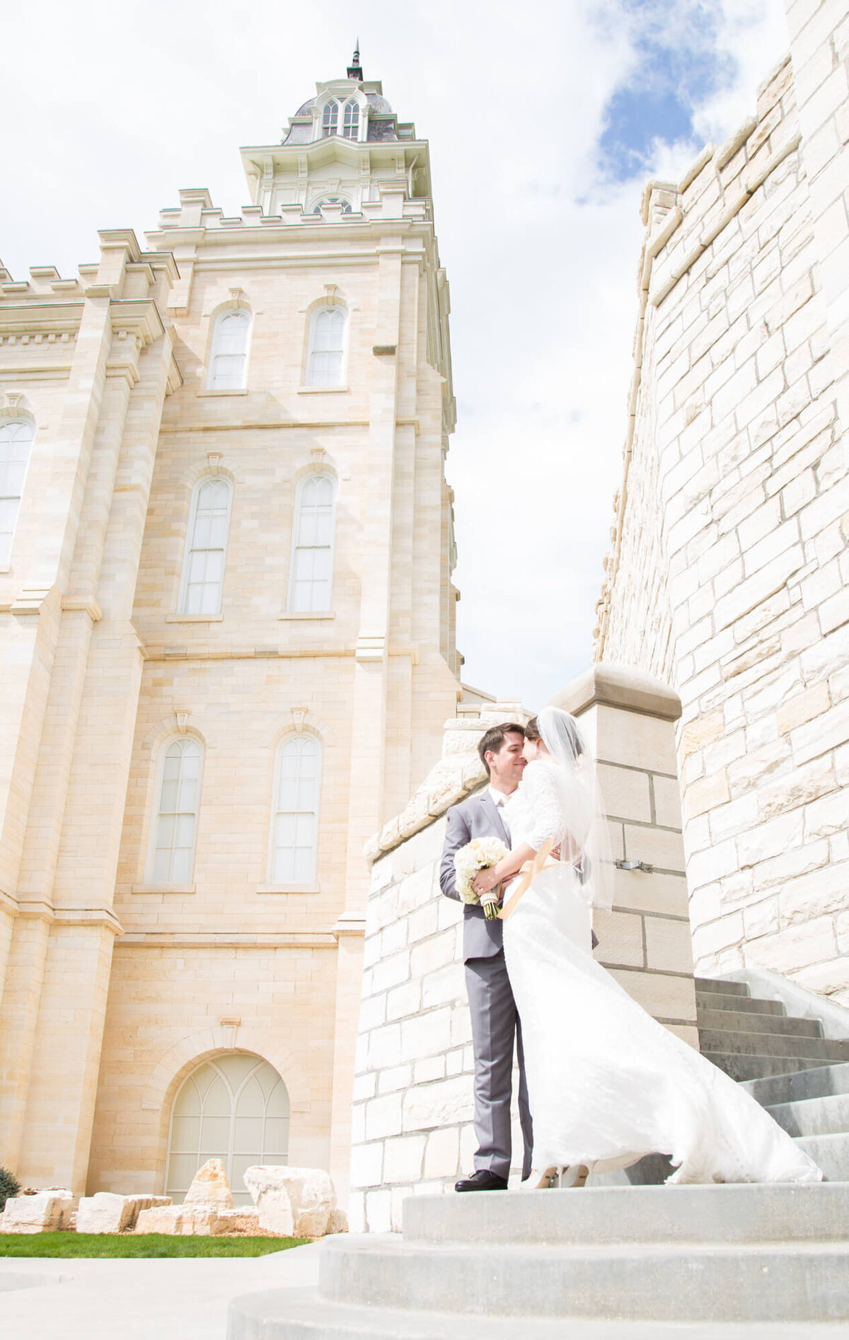 a bride and groom on the steps of a white brick building