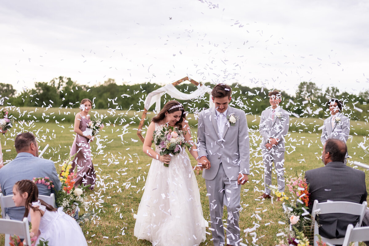newlywed celebration recessional bride and groom first kiss confetti wedding guests