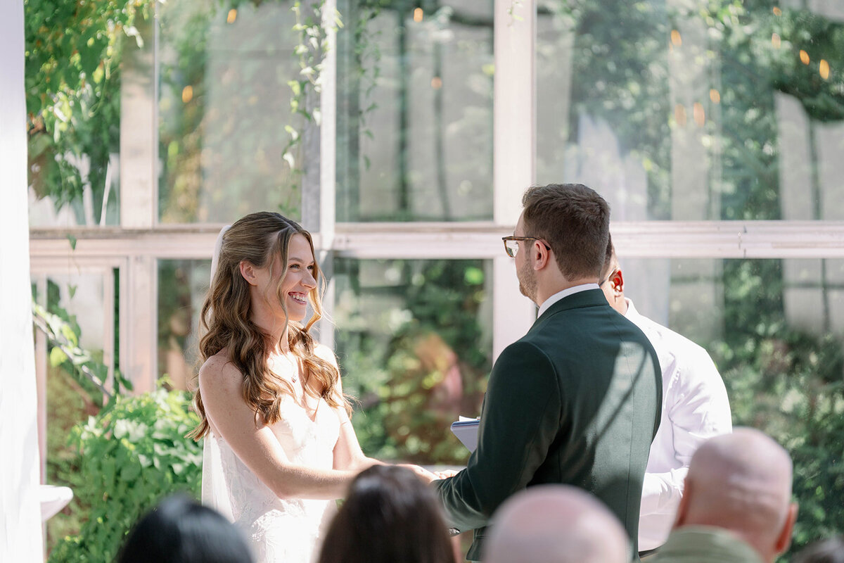 Detail photo of the bride and groom holding hands during their Ivy House greenhouse ceremony.