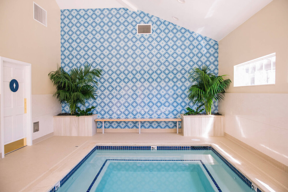 a indoor pool with a tile wall and plants
