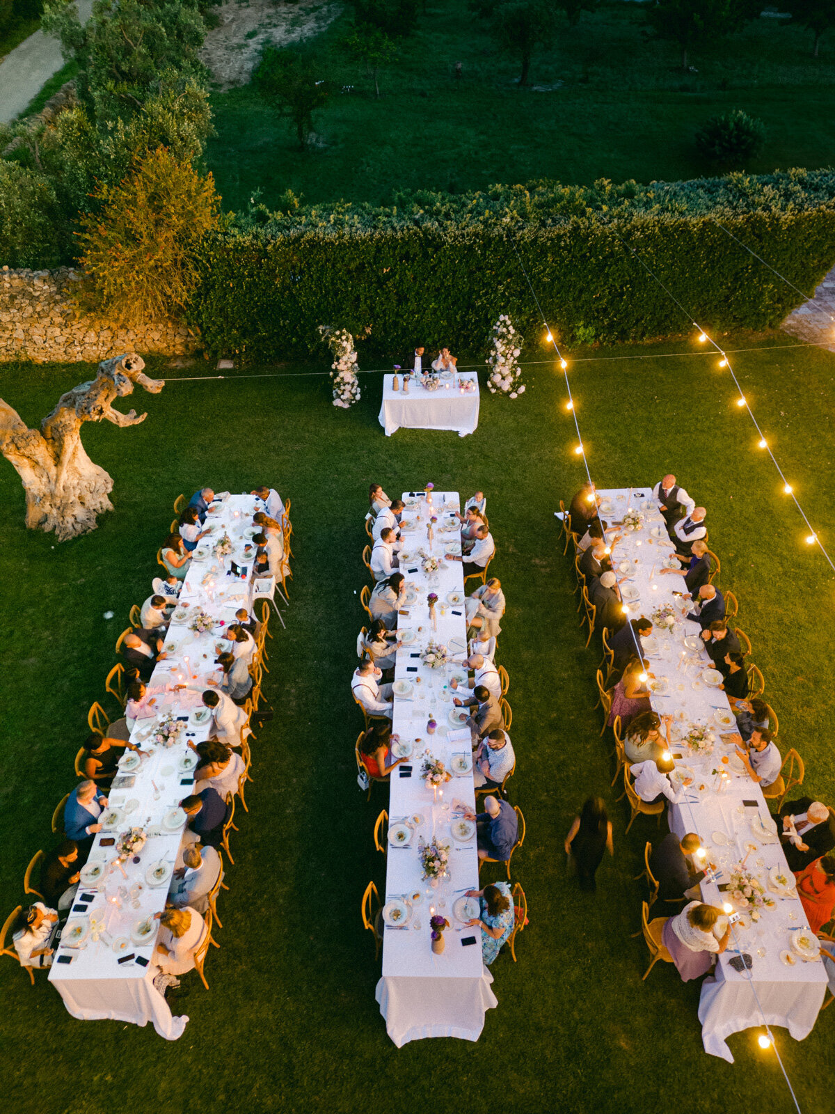 Luxury outdoor wedding dinner under string lights in Italy – elegant reception with long tables and guests celebrating under the stars