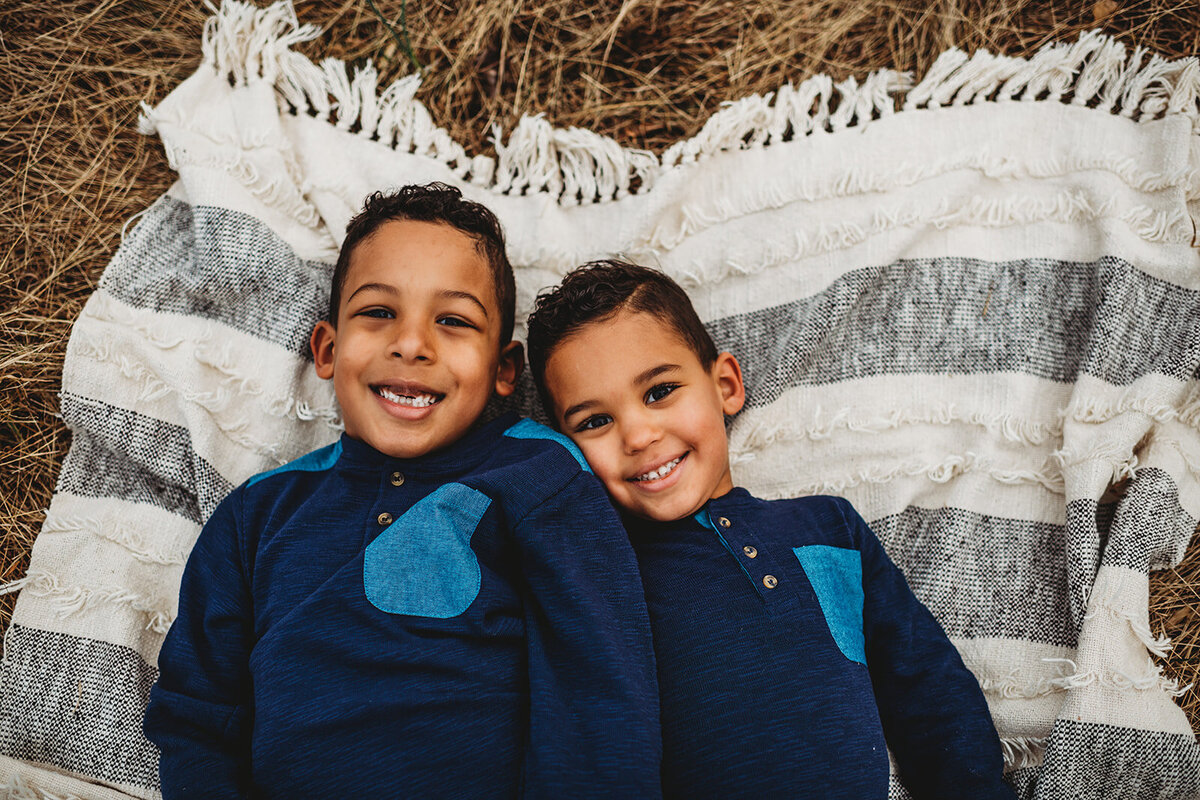 Baltimore photographers  photographs two little boys in blue shirts laying on the ground together on a blanket together