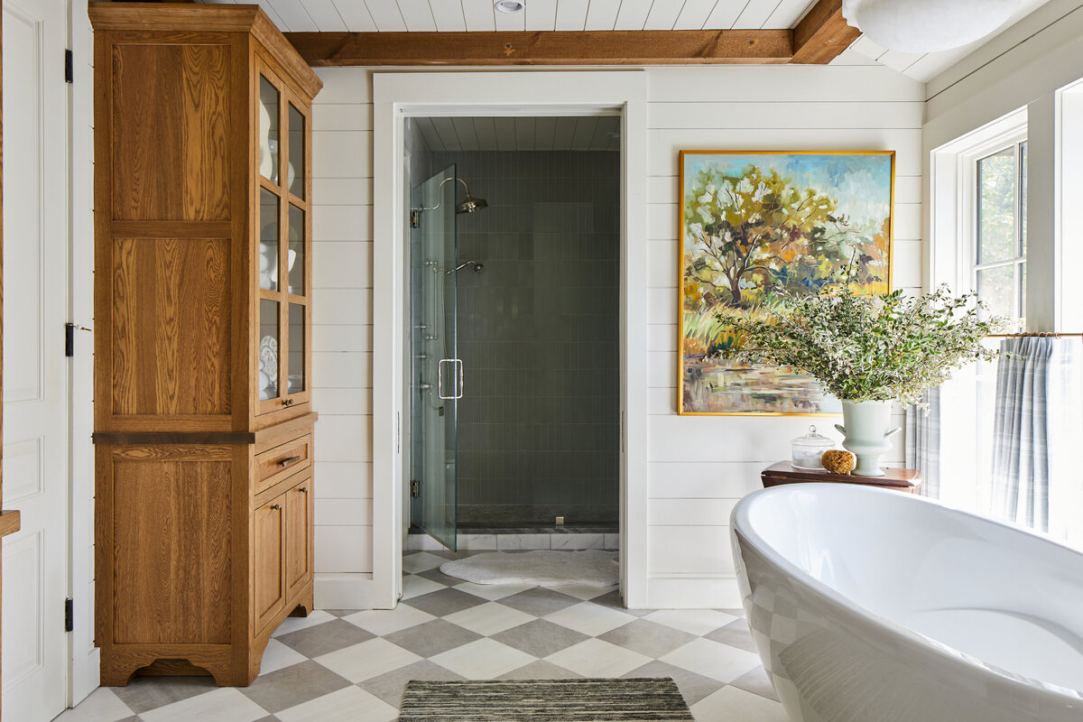 bright bathroom with large tub and light wood features