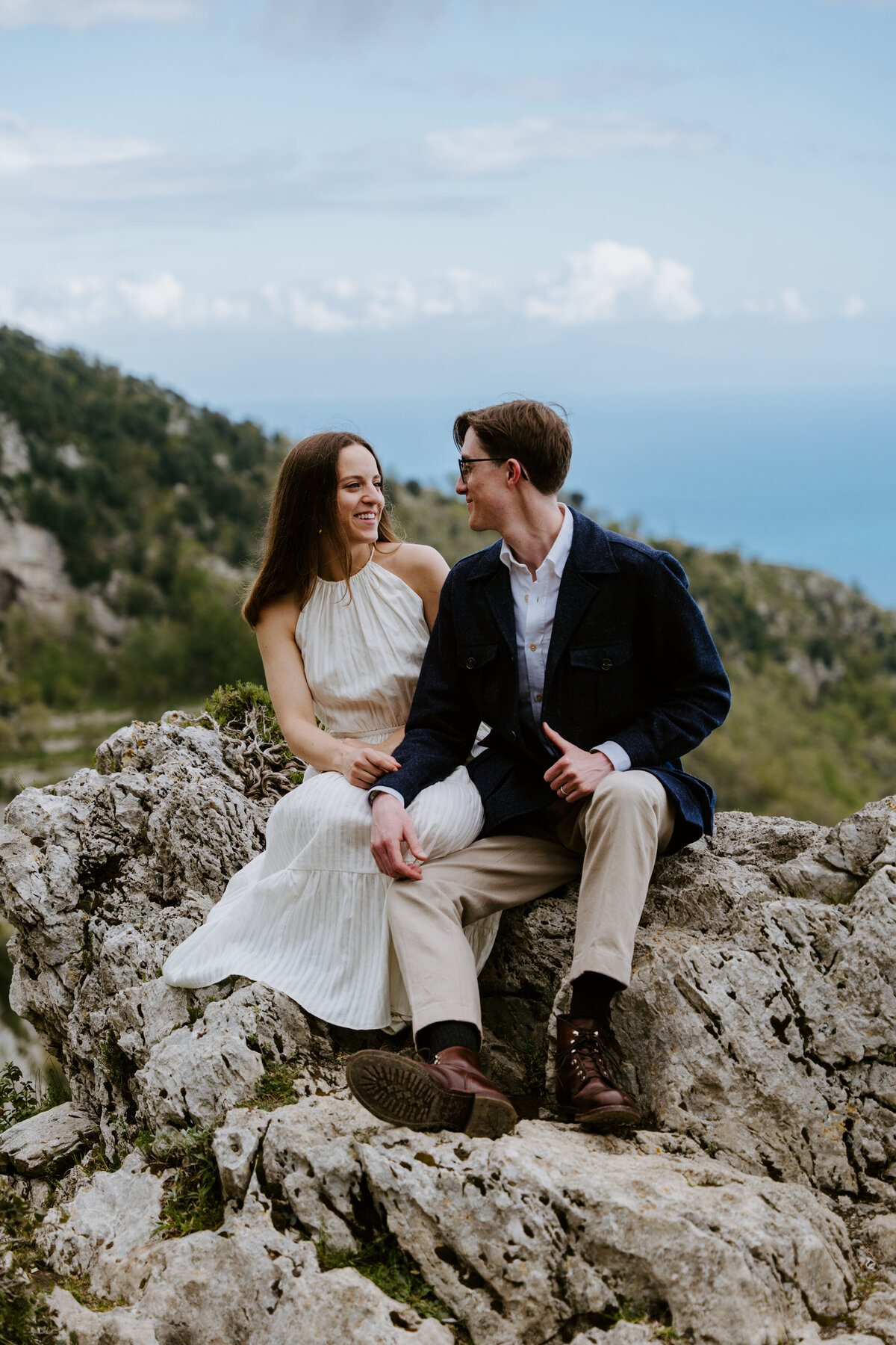 Couple sitting on rocks overlooking the sea.