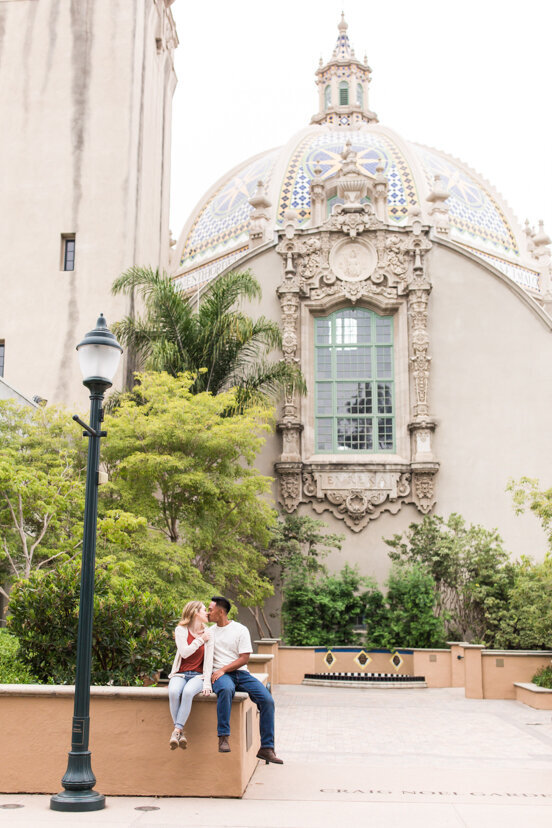 engaged couple sitting by balboa park museum san diego