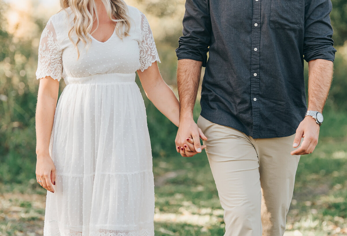 Couple holding hands and walking at their summer engagement session in London Ontario
