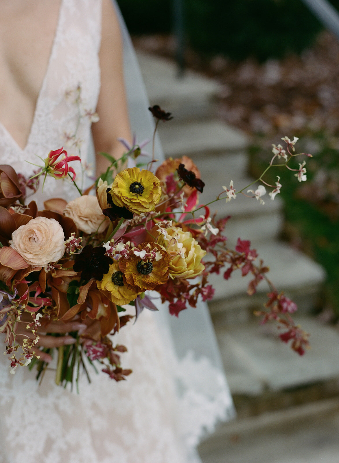 Organic artistic bridal bouquet with delicate blooms and texture. Fall bridal bouquet for private home wedding featuring orchids, ranunculus, and sweet peas. Textural bridal bouquet in a tasteful fall pallet of copper, lavender, gold, and ruby. Private property autumnal wedding in the hills of Tennessee. Design by Rosemary & Finch Floral Design in Nashville, TN.