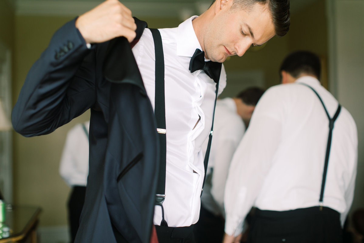 groom putting on suit jacket