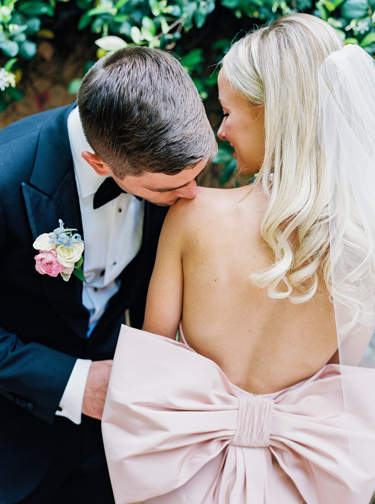 Romantic wedding photography capturing an intimate moment as the groom kisses the bride’s shoulder, creating a timeless and elegant image.
