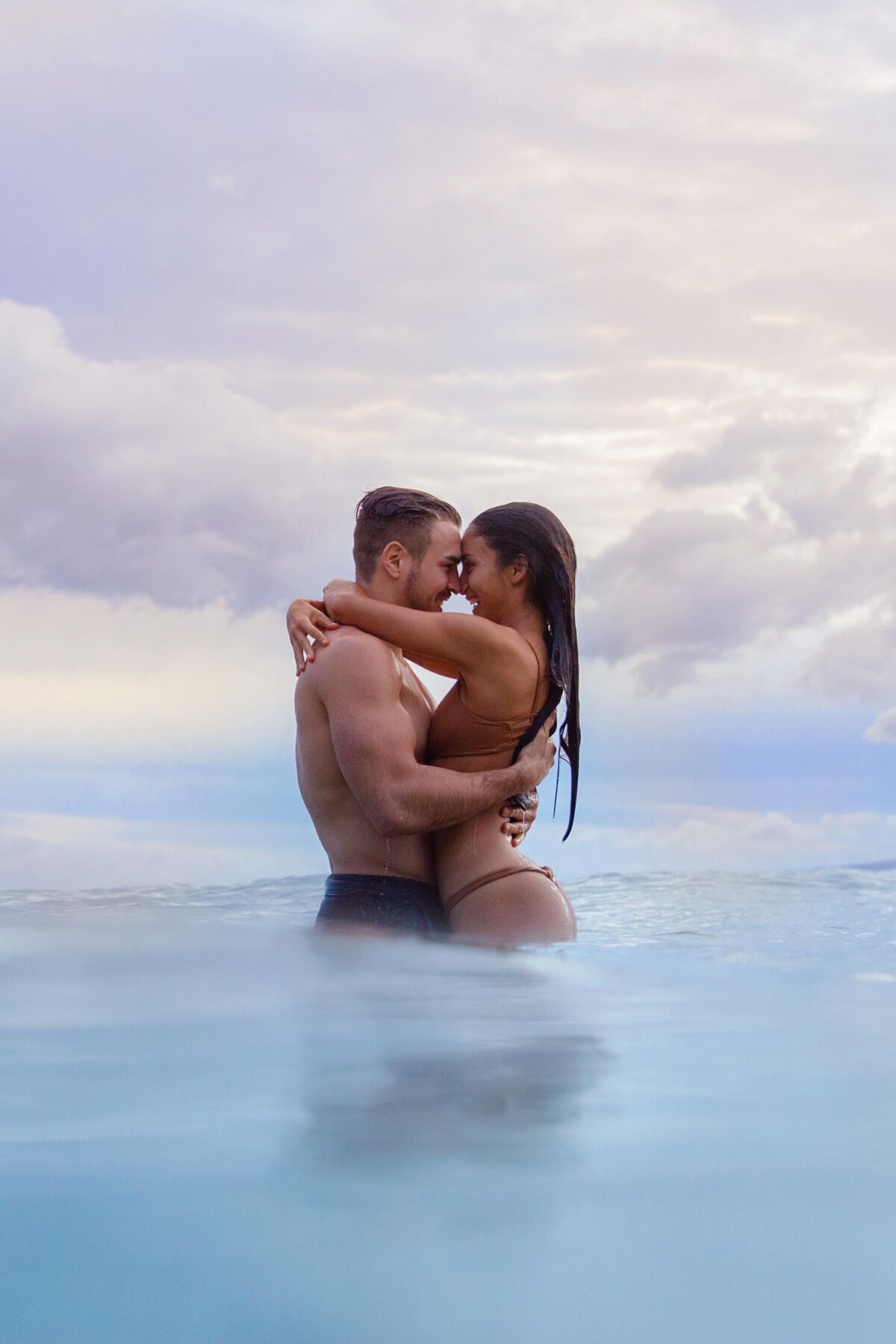 Moody cloudy image of romantic couple wearing swimear for their ocean portraits by Love + Water Photography