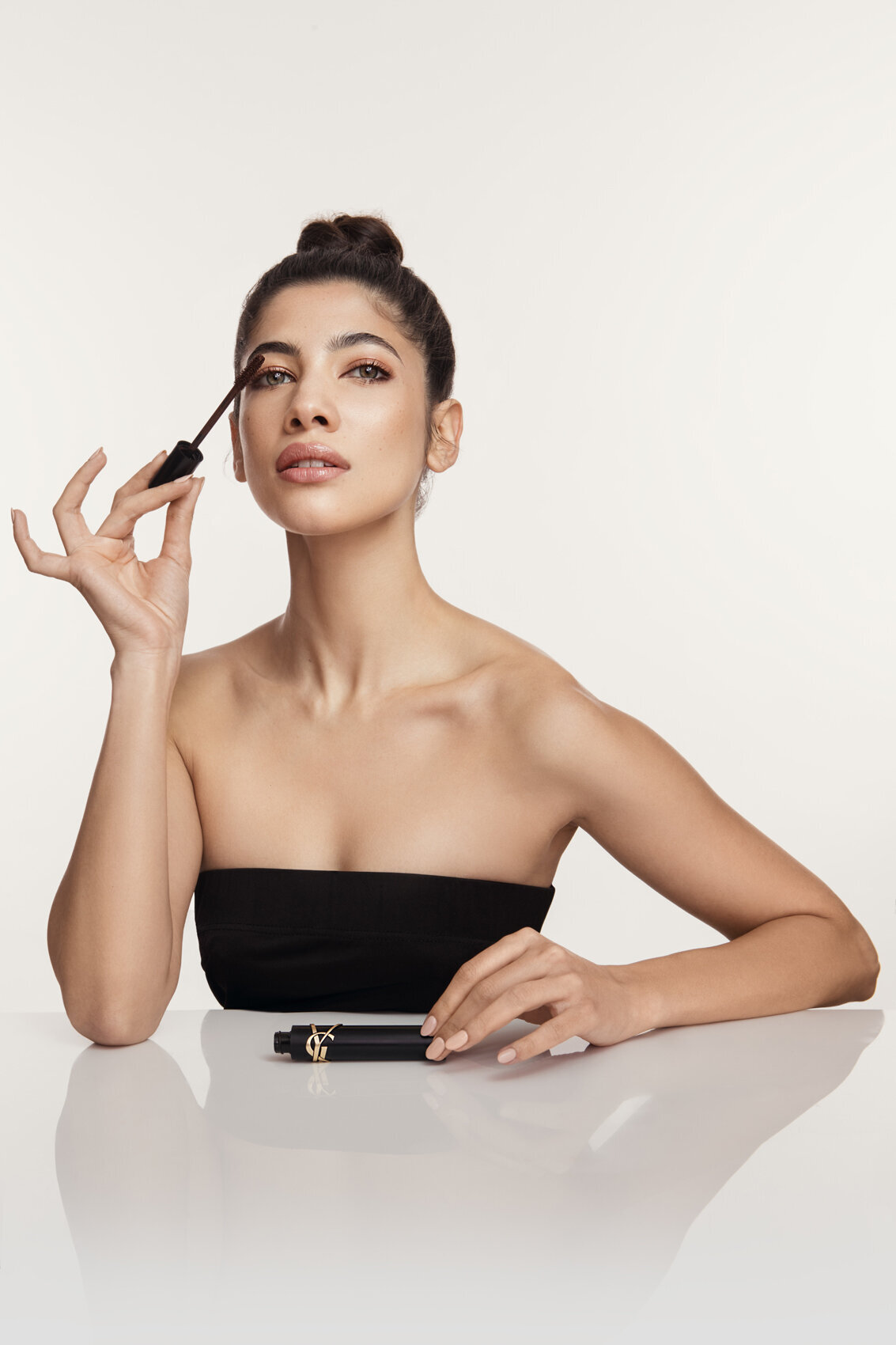 Apoorva posing elegantly with a YSL lipstick in a minimalist setting, captured by Ylva Erevall.