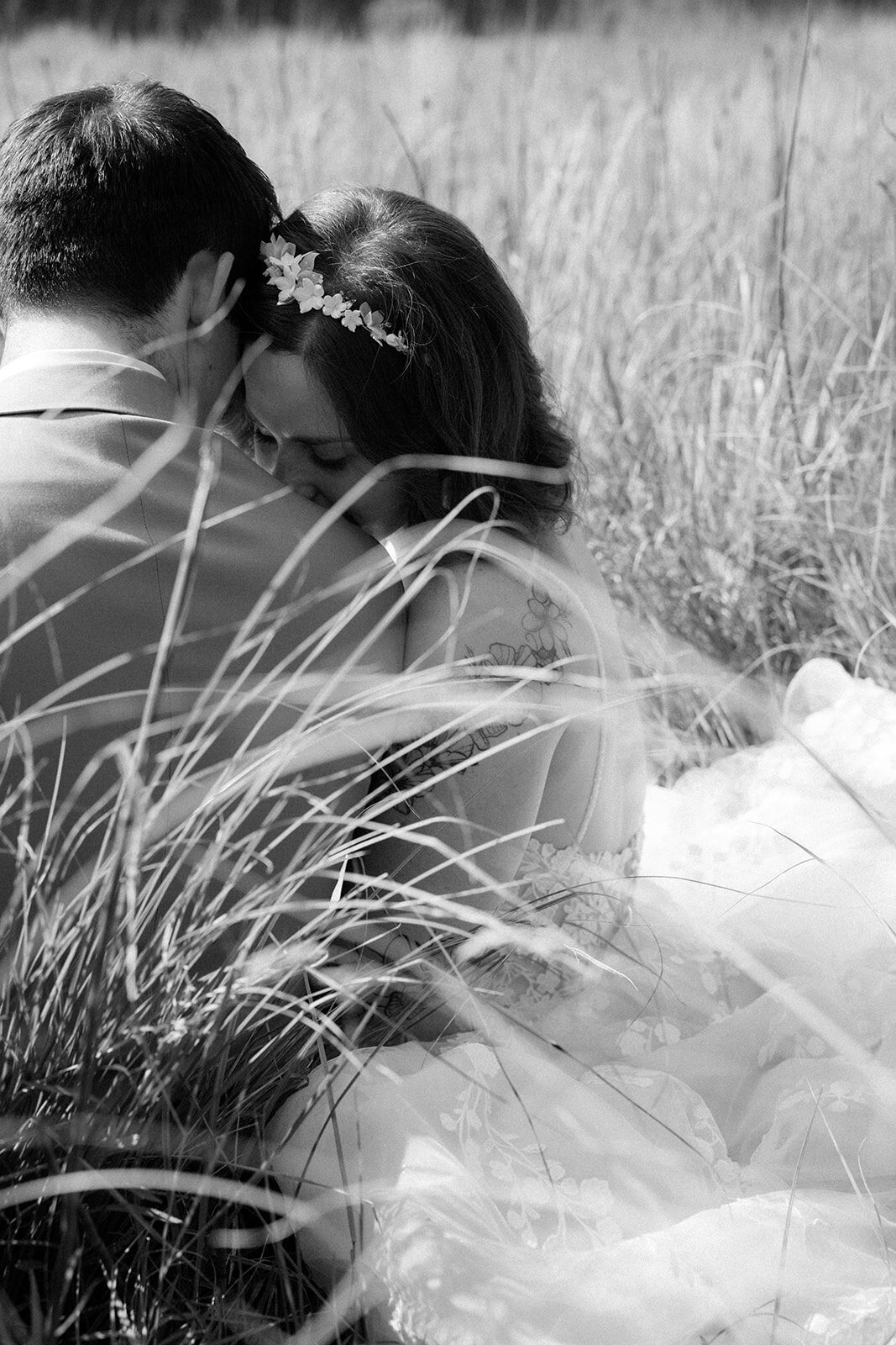 Bride leans her head into her grooms shoulder, while wearing her wedding gown on her wedding day.