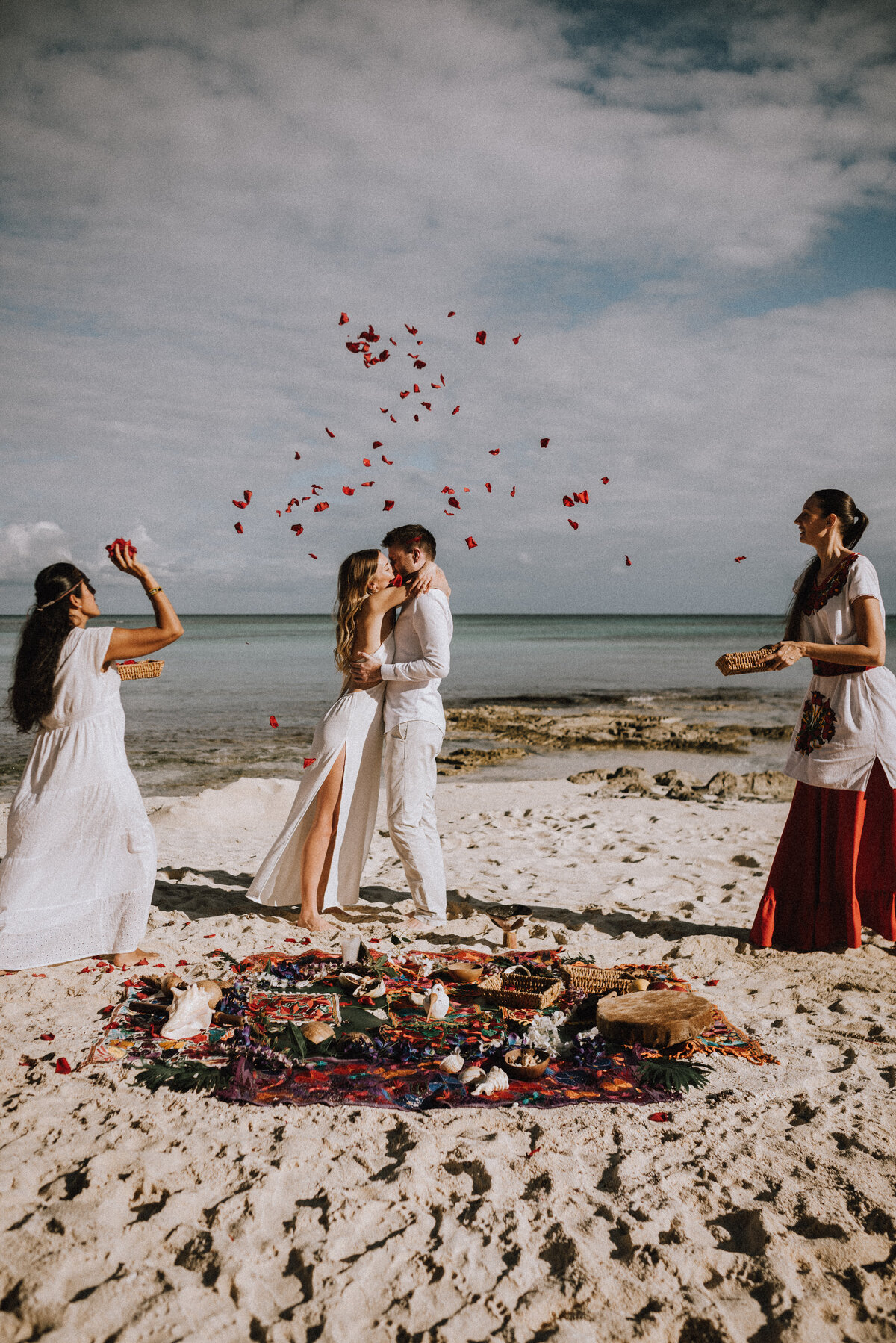 Bride and grooms first kiss, showered by flower petals during their spiritual elopement in Tulum, Mexico