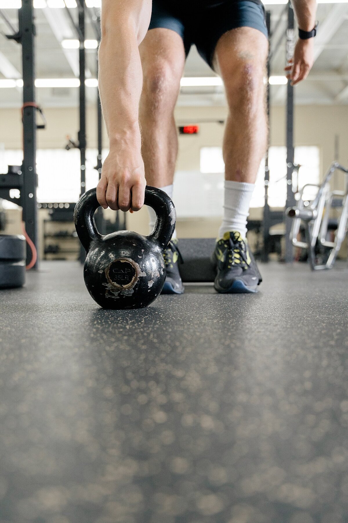 brand photography for a personal trainer with a man lifting a kettle bell in a gym photographed by brand photographer