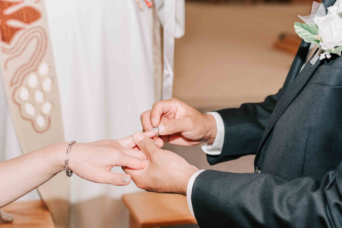 Groom placing ring on brides finger.