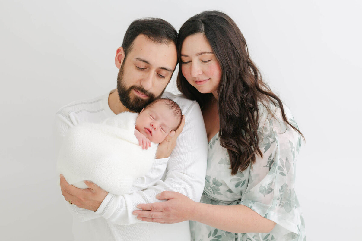 Mom and dad looking down at their sweet newborn baby in their arms