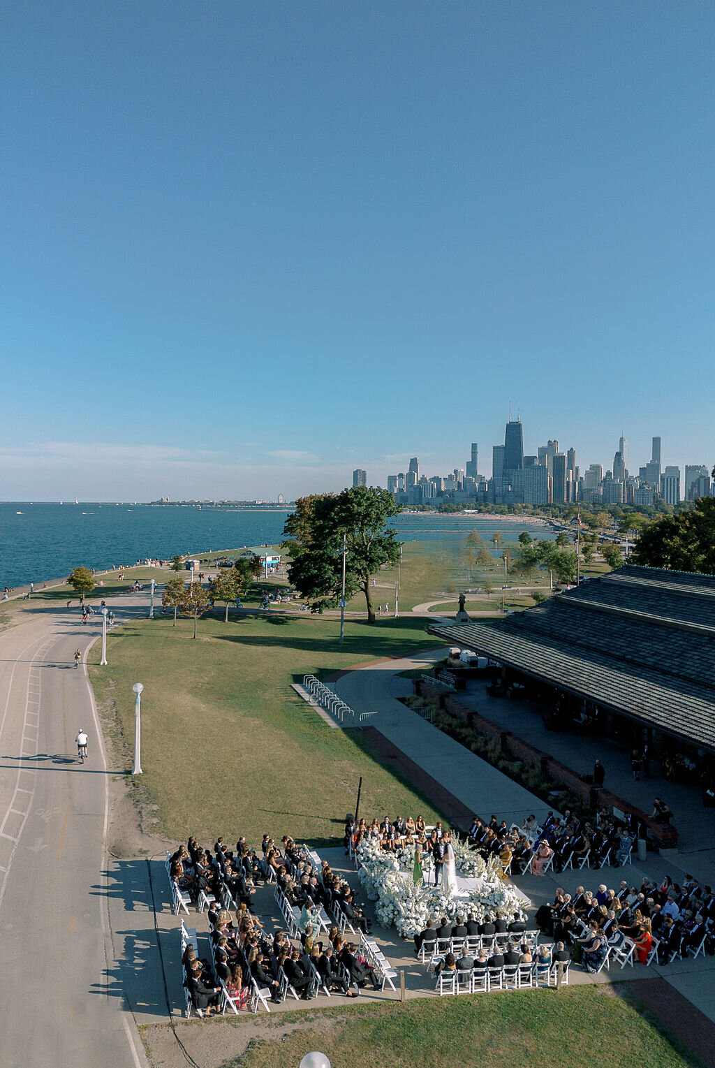 A stunning overhead shot of a wedding ceremony at Chicago’s Theater on the Lake, with the city skyline and Lake Michigan in the background.