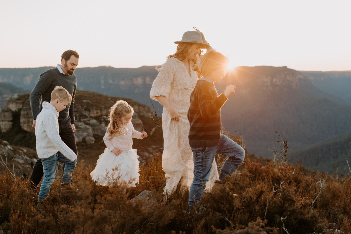 Family of five walking through the Blue Mountains at sunset, captured during a natural outdoor photography session with golden light and scenic cliffs in the background.