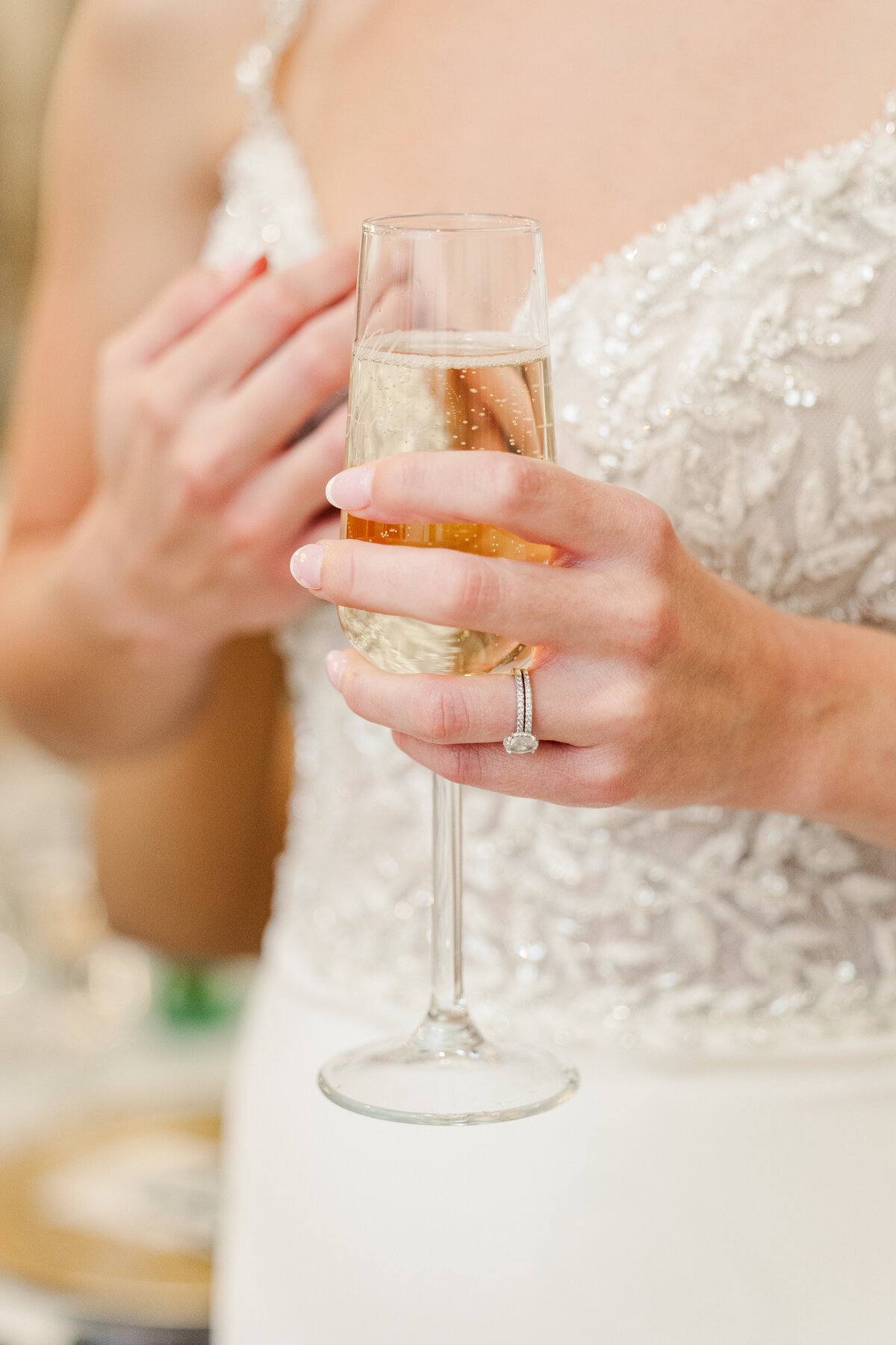 A close-up of the bride’s hand holding a champagne flute, highlighting her ring and intricate gown details—elegant reception detail from a luxury Westlake wedding.