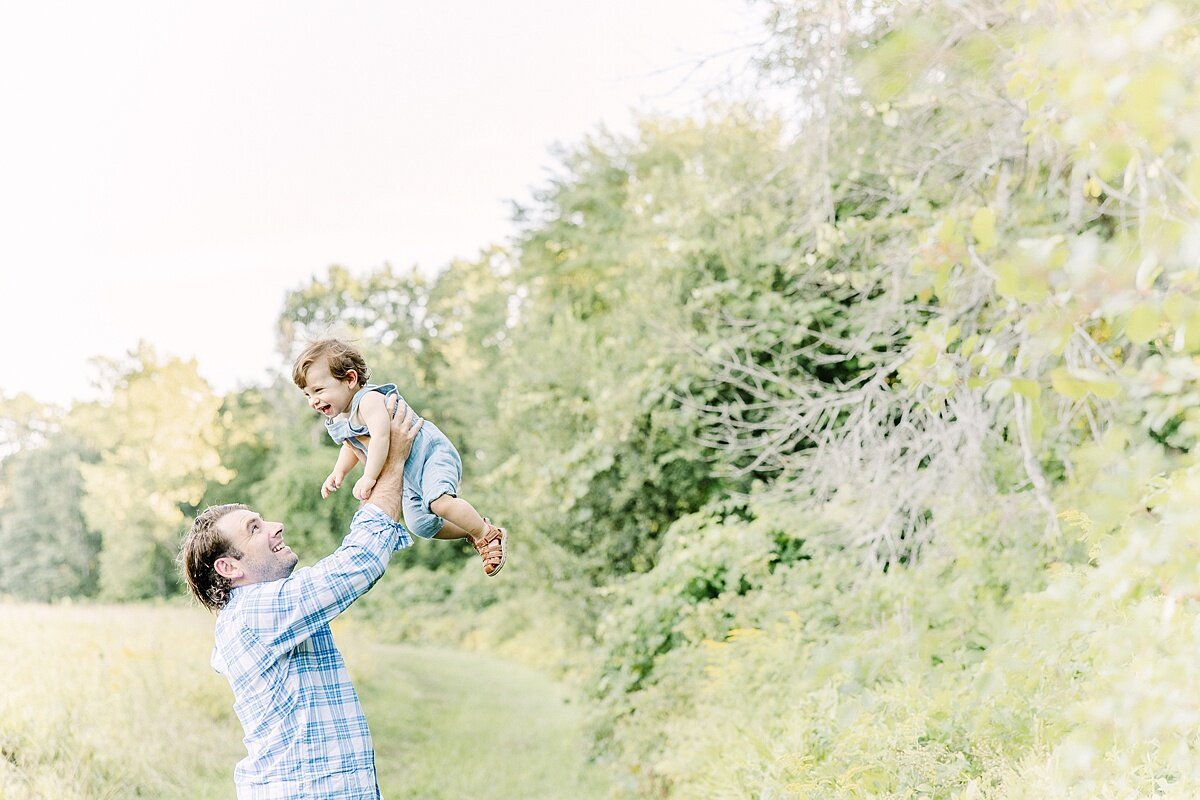 dad holds son in air duirng summer  family photo session with Sara Sniderman Photography in Natick Massachusetts