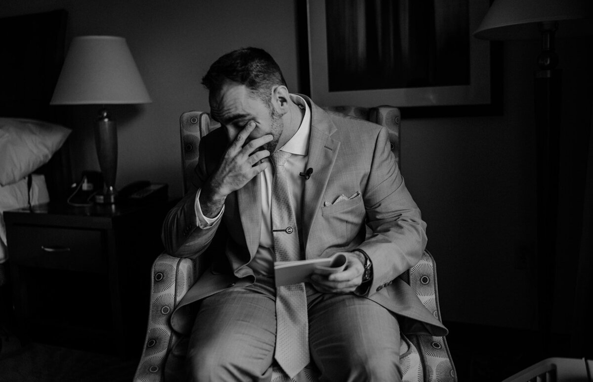 groom wipes a tear from his eye reading a note from bride photo. by cait fletcher photography